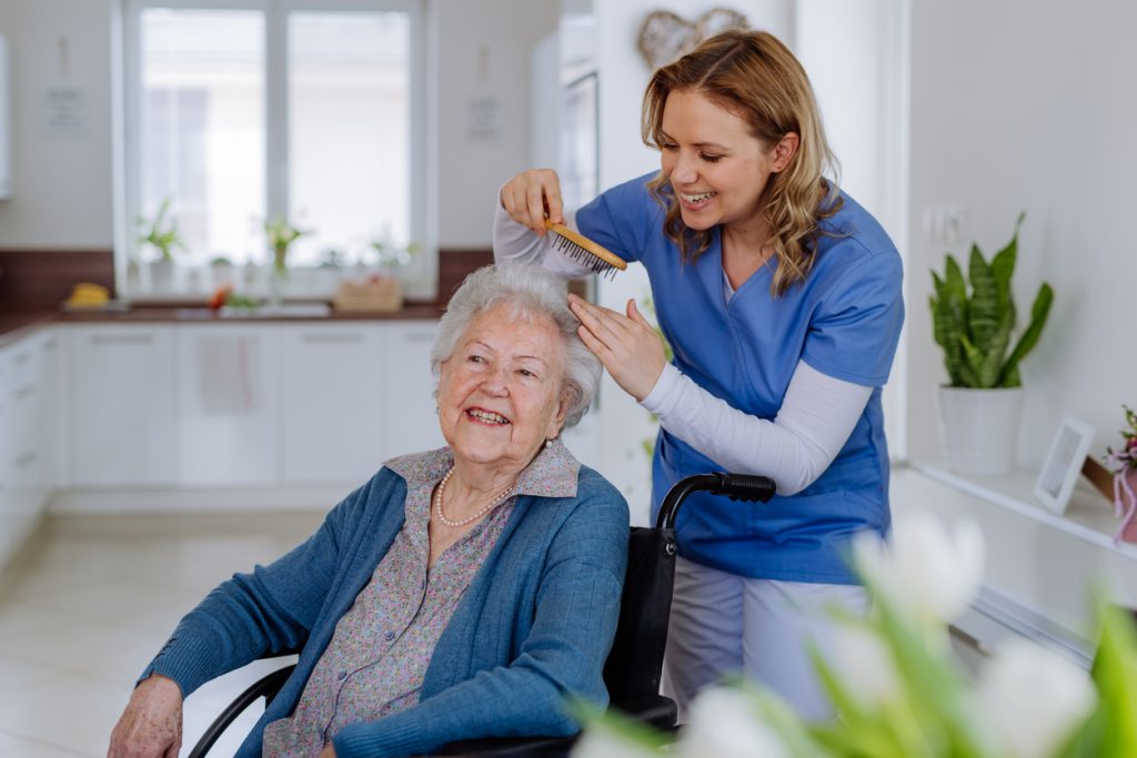 Nurse doing hairstyle to her senior woman client.