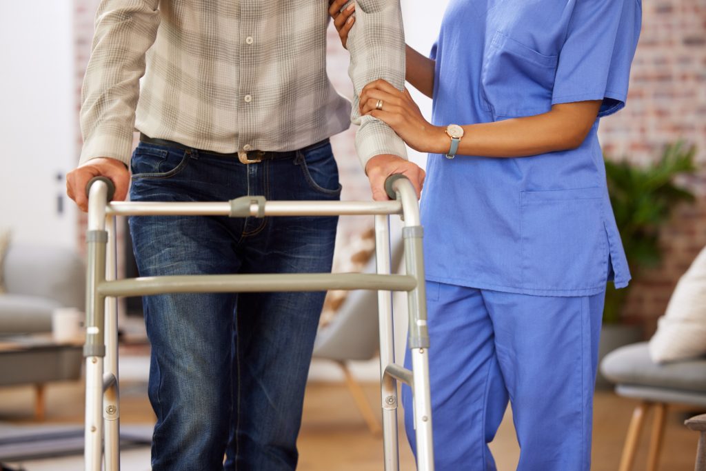 Shot of a nurse helping her elderly patient use their walking frame