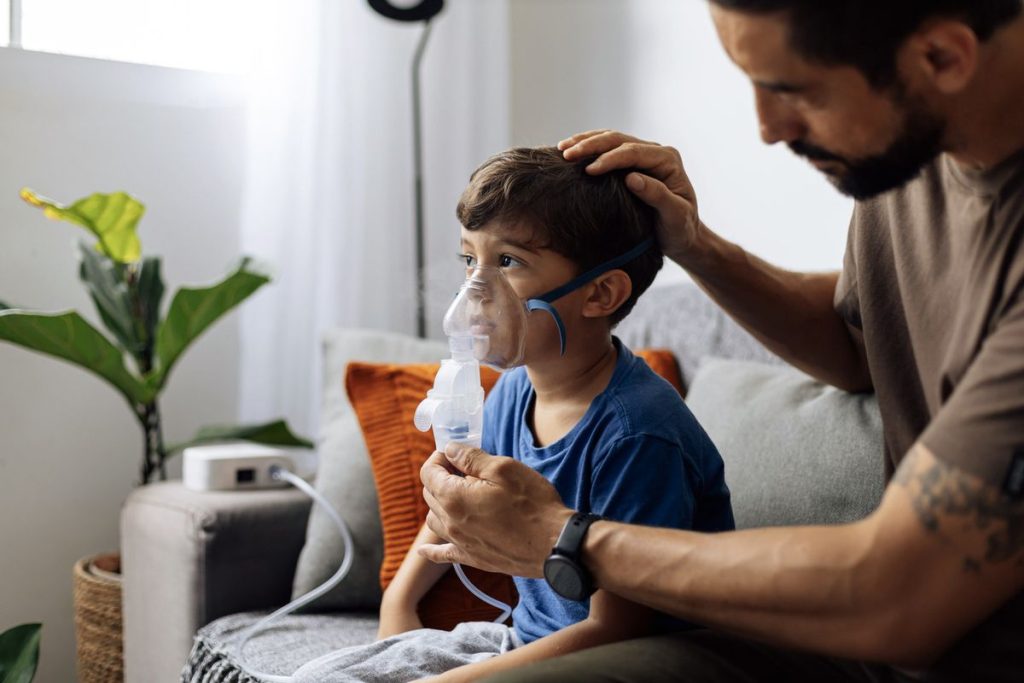 Father helping child nebulizer therapy at home Father comforting a young child during a nebulizer treatment at home