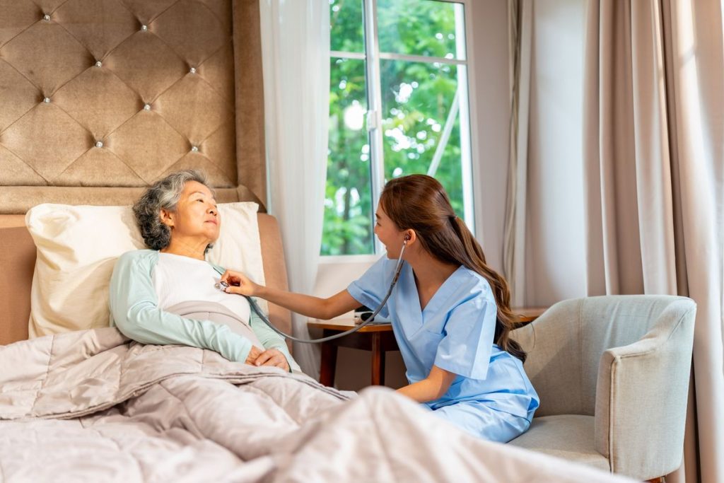 Nurse assessing senior breathing at home Home health nurse assessing a senior client’s breathing with a stethoscope at home